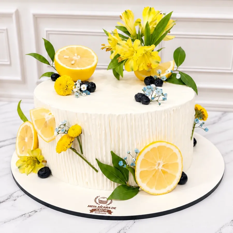 Bolo branco decorado com limão siciliano, flores amarelas e mirtilos